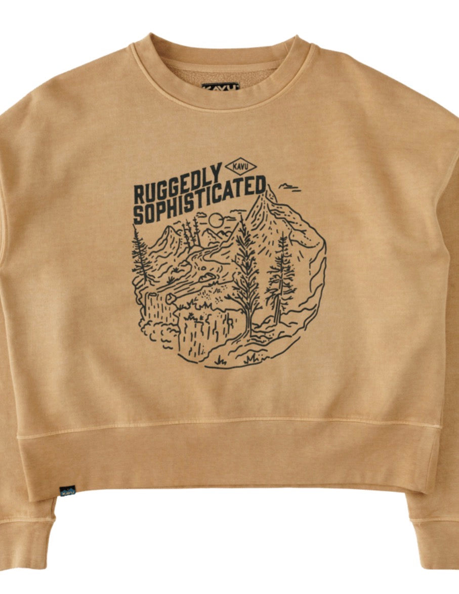 A cropped crewneck sweatshirt in a warm tan color, featuring a black line art graphic of a mountain scene with the text 'RUGGEDLY SOPHISTICATED' and a small '1967' logo. The sweatshirt is laid flat against a white background.