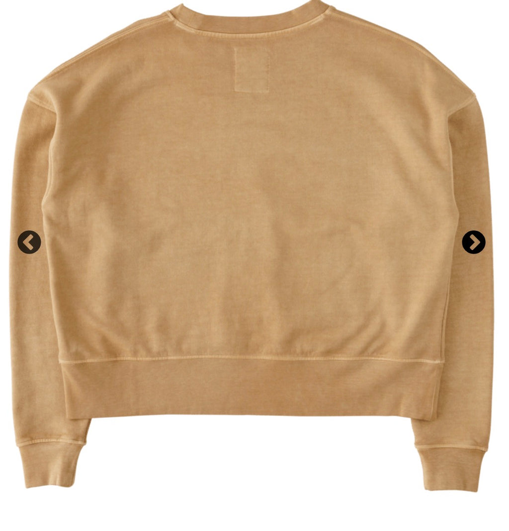 A cropped crewneck sweatshirt in a warm tan or camel color, shown from the back. It features two small black circular arrow icons on the upper sleeves and a blank rectangular patch on the upper back.